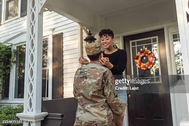 una donna lesbica accoglie la sua ragazza veterana militare alla porta d'ingresso di casa sua - uniforme militare foto e immagini stock