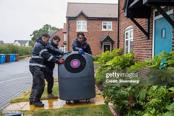 Engineers move an Octopus Energy Cosy 6 heat pump towards a house prior to installation in Derby, UK, on Tuesday, July 15, 2025. In order for the...