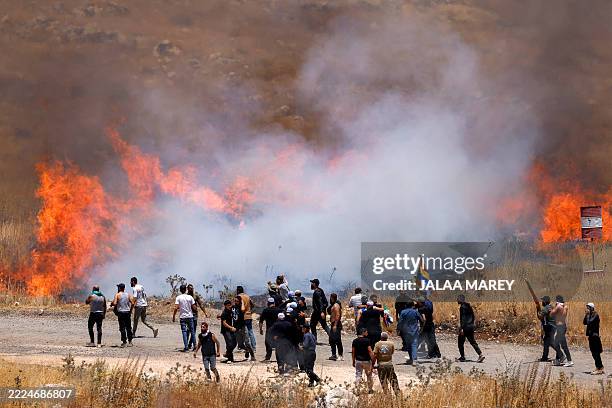 Members of Syria's Druze community walk through tear gas fumes released by Israeli forces to disperse them, as they gather along the dividing line to...