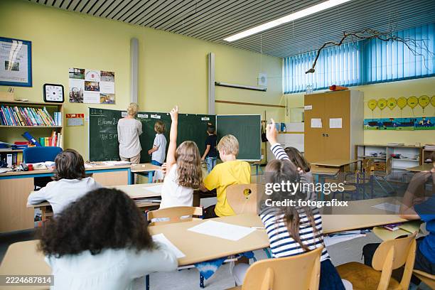 eine unterrichtsstunde in einer grundschulklasse, erklärt eine lehrerin, kinder machen aktiv mit - schulkind stock-fotos und bilder