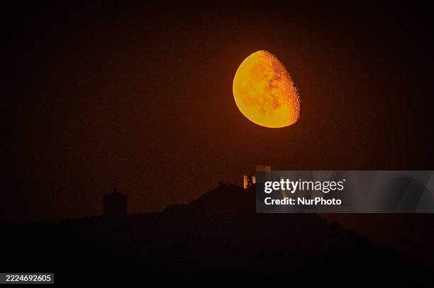 Waning gibbous moon rising behind Rocca Calascio Castle and Santa Maria della Pietà Church is seen in Calascio, Italy, on July 15th, 2025.