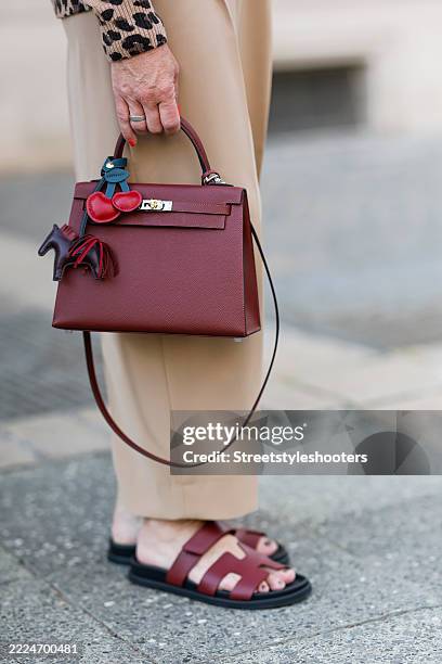 Influencer Simone Adams, wearing wide leg trousers by Rossi, brown sandals by Hermes and a beardaux red bag by Hermes, seen on July 11, 2025 in...