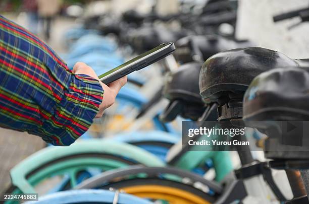asian female use smart phone to scan the qr code on a shared bike to unlock it. - sharing economy stock-fotos und bilder