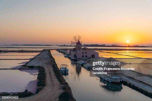 sunset over salt pans and windmill, marsala, sicily, italy. - trapani provincie stockfoto's en -beelden