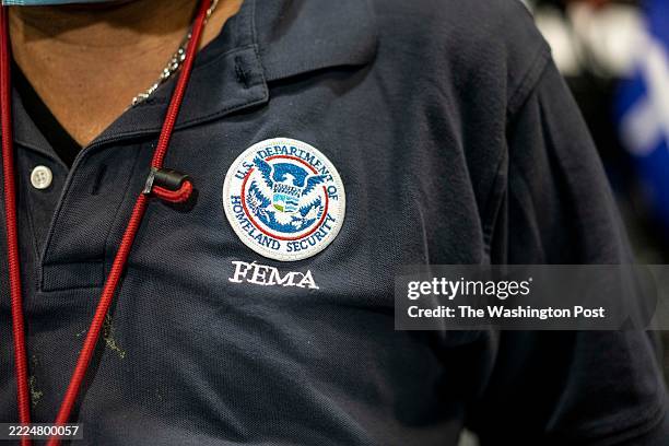 Worker Jean Fequiere with logo on shirt at a shelter for those displaced by Hurricane Ian at Hertz Arena in Estero Fla.