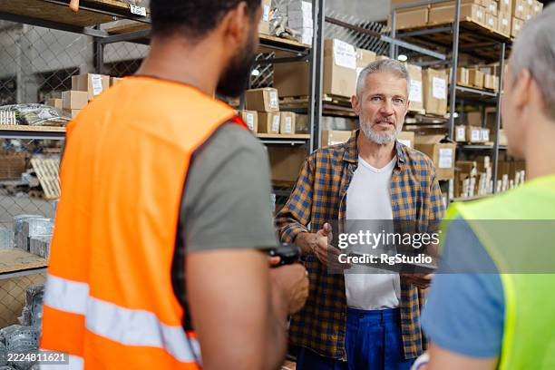 warehouse manager explaining logistics to workers with digital tablet - explaining stock pictures, royalty-free photos & images