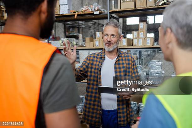 warehouse manager explaining logistics to workers using digital tablet - explaining stock pictures, royalty-free photos & images
