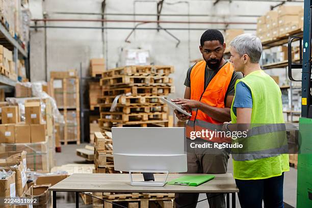 warehouse workers discussing logistics using digital tablet and computer - wholesaler stock pictures, royalty-free photos & images