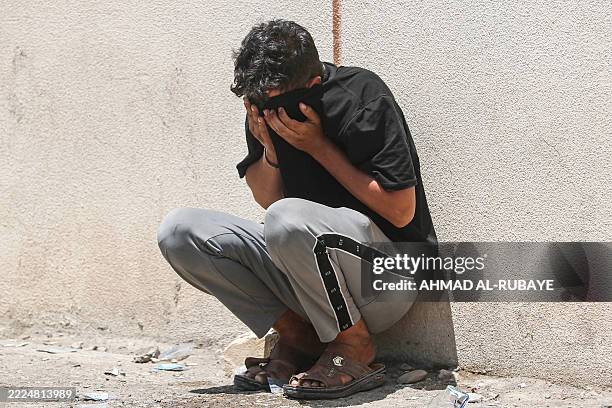 Relative covers his face as he waits outside the forensic department of the al-Zahraa Hospital on July 17 after a fire tore through the newly opened...