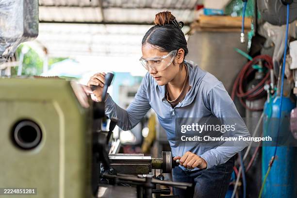 skilled asian woman machinist working on a lathe machine in a workshop - production line worker stock pictures, royalty-free photos & images