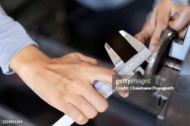 primer plano de las manos de una ingeniera midiendo el componente metálico con el calibrador vernier - calibrador fotografías e imágenes de stock