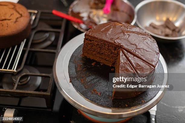 rich, moist chocolate cake sits on a rotating cake stand, a single slice cut out, tempting viewers with its decadent appeal - chocolate cake stock pictures, royalty-free photos & images