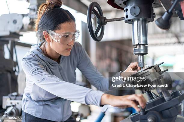 abile meccanica asiatica che lavora una parte del motore su un trapano a colonna in un'officina - operaio metallurgico foto e immagini stock