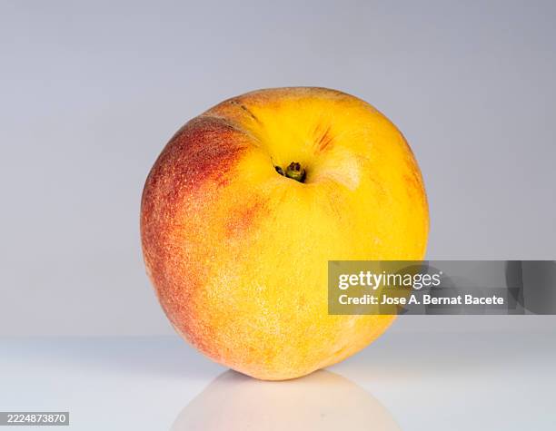 close-up of a whole peach reflected on a shiny white background. - nectarine stock pictures, royalty-free photos & images