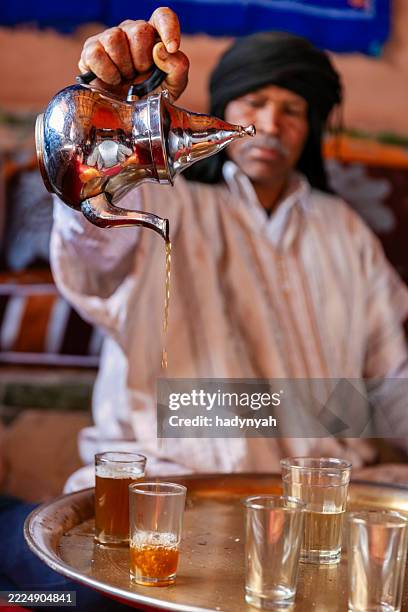 moroccan man preparing maghrebi mint tea. - kaftan stock pictures, royalty-free photos & images