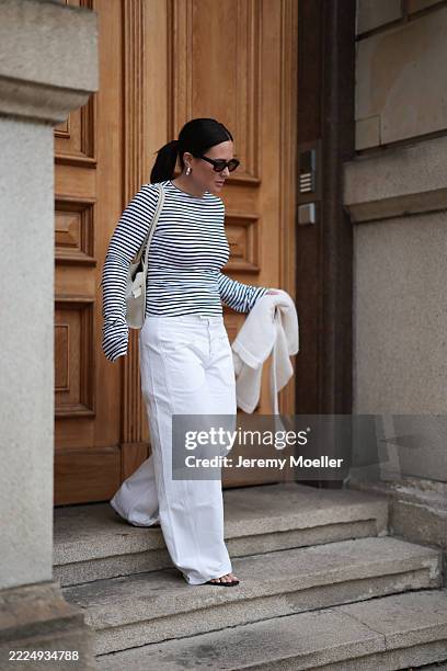 Lou Beyer is seen wearing rectangular-shaped sunglasses with a bold black frame and orange lenses from Jacques Marie Mage; chunky silver hoop...