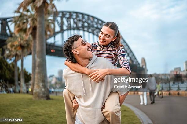 joyful young hispanic couple enjoying sydney outdoors by iconic bridge - sydney harbour bridge stock pictures, royalty-free photos & images