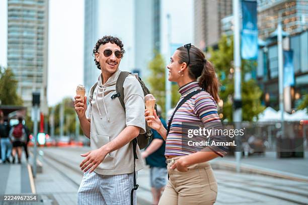 smiling hispanic couple enjoying ice cream in sunny sydney - couple crossing street stock pictures, royalty-free photos & images