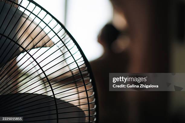 fan on the background of woman opening the curtains at home - hittegolf stockfoto's en -beelden
