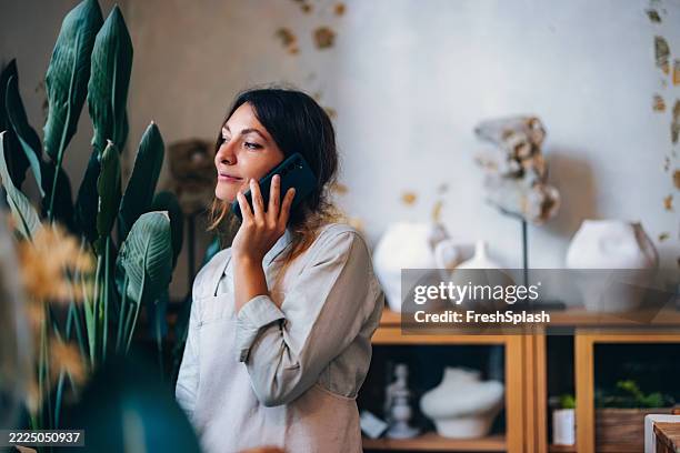 donna che lavora su una telefonata in un elegante negozio di ceramica - studio di design foto e immagini stock