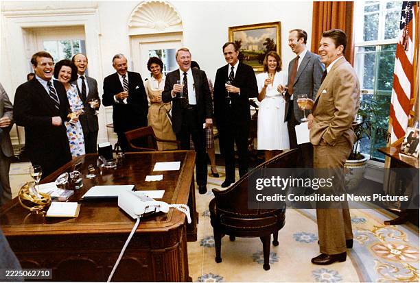 In celebration of the passage of a tax bill, US President Ronald Reagan leads a toast with members of his staff in the White House's Oval Office,...