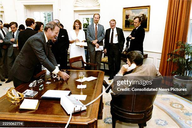 In celebration of the passage of a tax bill, White House Chief of Staff James A Baker III offers a glass of champagne to US President Ronald Reagan ,...