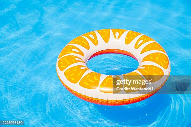 colorful inflatable pool float in a sunny swimming pool - tubing stock pictures, royalty-free photos & images