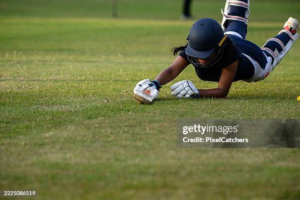 teenage female batsman takes a dive sliding with cricket bat to score - cricket bat stock pictures, royalty-free photos & images