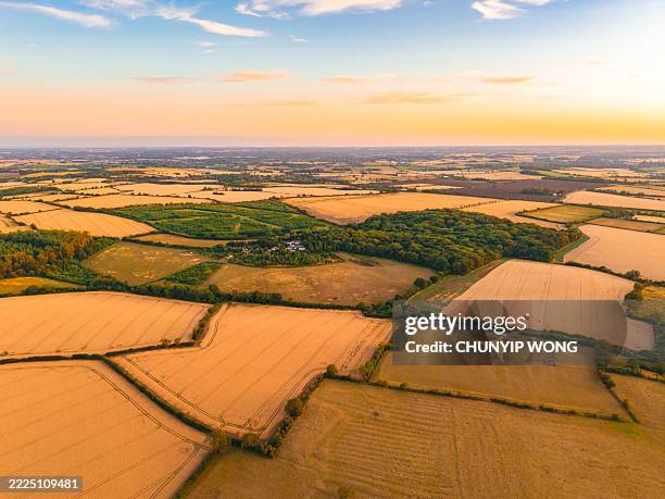 sunset illuminating farmland and fields from above - patchwork landscape stock pictures, royalty-free photos & images