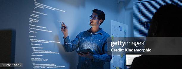 hispanic latin american man, software engineer developer use computer projection screen presentation, work on program coding with coworker at night. programming language development technology concept - programador imagens e fotografias de stock