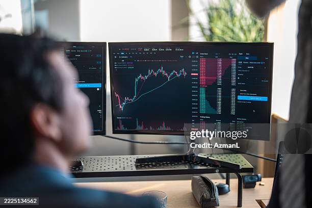 male stock brokers analyzing trading data on dual monitors - stock broker office stock pictures, royalty-free photos & images