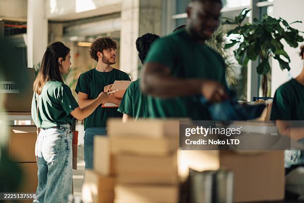 voluntarios preparando cajas de donaciones en una organización benéfica - responsabilidad social fotografías e imágenes de stock