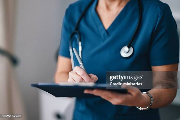 professionnel de la santé rédigeant des notes dans un cabinet médical - agenda électronique photos et images de collection