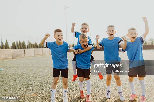 junior soccer team posing together on the field in blue uniforms - groepsfoto stockfoto's en -beelden