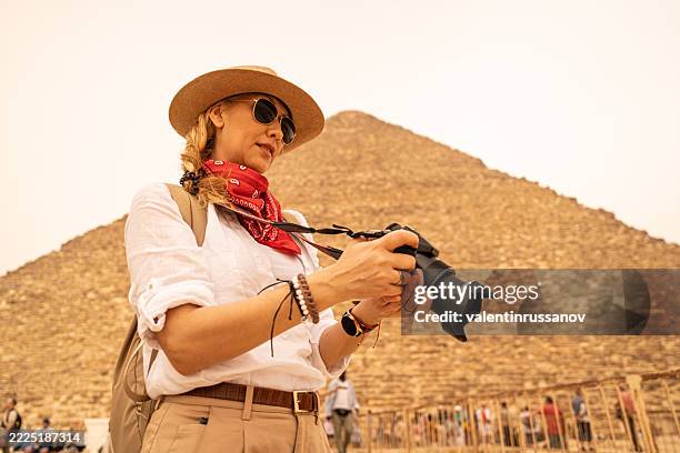 female photographer in vacation standing with photo camera in front of the great pyramids. egypt, cairo - giza - giza pyramids stock pictures, royalty-free photos & images