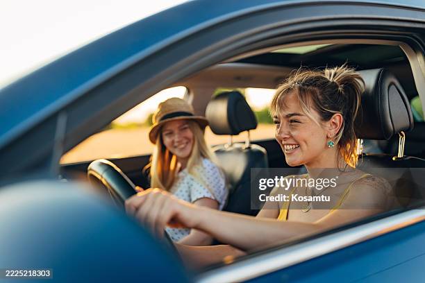 two best friends enjoy a car trip on their summer vacation. they smile, create shared memories and enjoy each other's company - rijden een motorvoertuig besturen stockfoto's en -beelden