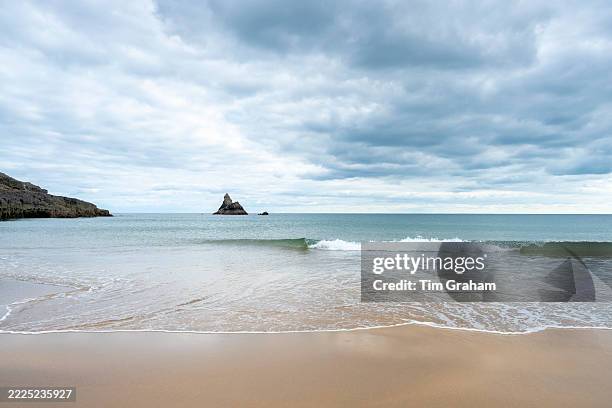 Church Rock, a limestone stack, and Broad Haven South Beach, an idyllic sandy beach with waves gently lapping near Bosherston in South Pembrokeshire,...