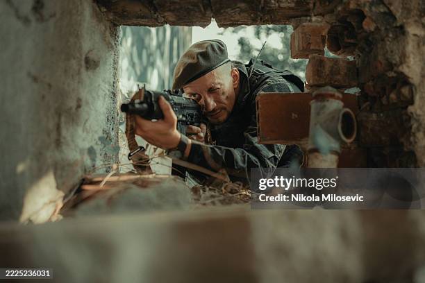 soldato tattico che punta il fucile tra le rovine durante le operazioni di combattimento - cecchino foto e immagini stock