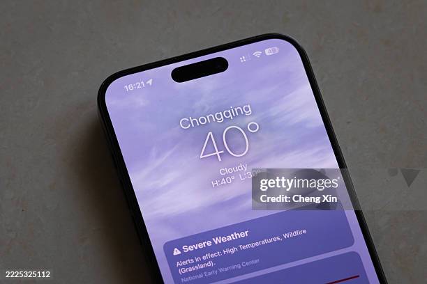 Smartphone placed on the floor displays a weather app showing a temperature of 40°C with cloudy conditions and a severe weather warning in Chongqing...