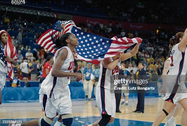 American basketball players Yolanda Griffith and Natalie Williams, whose face is covered by the American flag they parade after the gold-medal game...