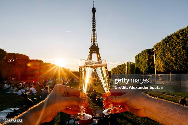 two persons toasting with champagne on champ-de-mars in-front of eiffel tower at sunset, personal perspective view, paris, france - champagne tower stock pictures, royalty-free photos & images
