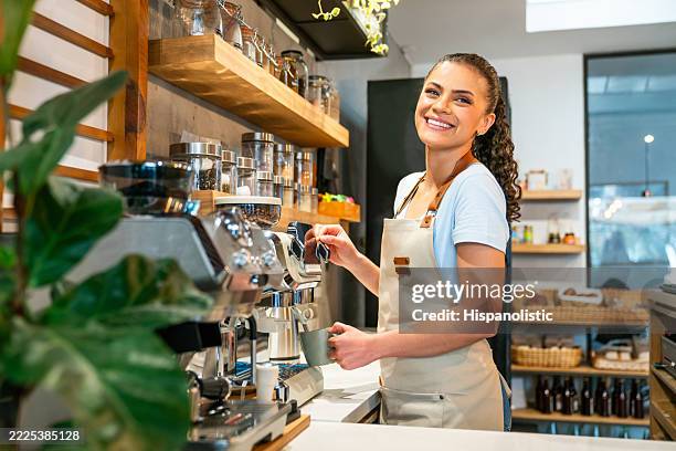 happy barista making a cup of coffee while working at a cafe - barista stock pictures, royalty-free photos & images