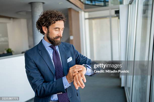 businessman checking time on wristwatch in modern office - checking the time stock pictures, royalty-free photos & images