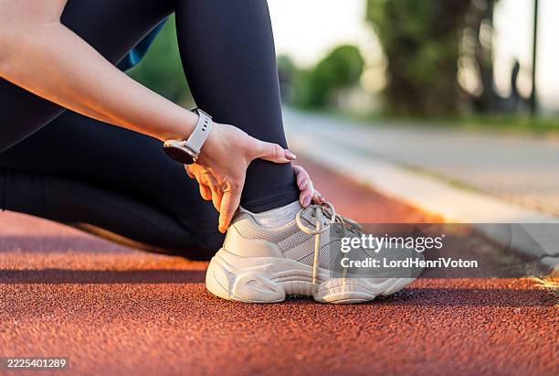 female athlete experiencing ankle pain on running track - ligament stock pictures, royalty-free photos & images