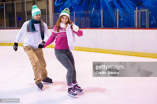young smiling couple ice skating in the ice skating rink in winter - ice skater stock pictures, royalty-free photos & images