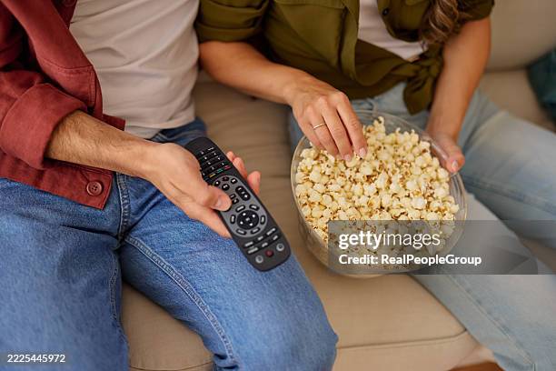 couple relaxing on sofa, watching television and eating popcorn - home cinema system stock pictures, royalty-free photos & images