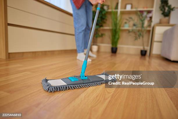 hausfrau reinigt laminatboden mit mikrofasermopp im wohnzimmer - mikrofaser stock-fotos und bilder