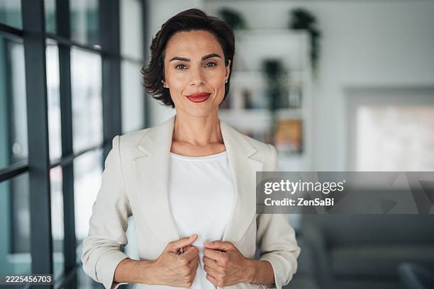 beautiful young business woman standing while smiling looking at camera in the office - realizador imagens e fotografias de stock