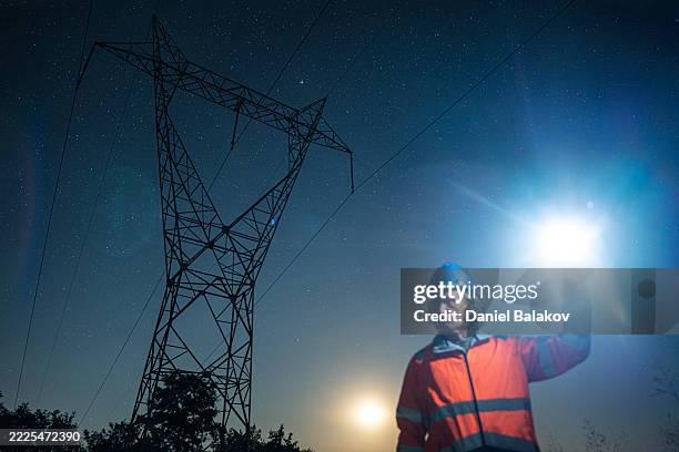 electrical engineer using flashlight to inspect high voltage power line at night - apagão imagens e fotografias de stock