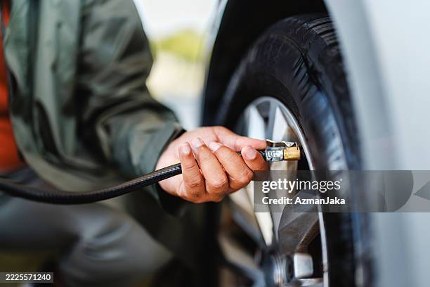 primer plano de la mano inflando el neumático del coche - neumático fotografías e imágenes de stock